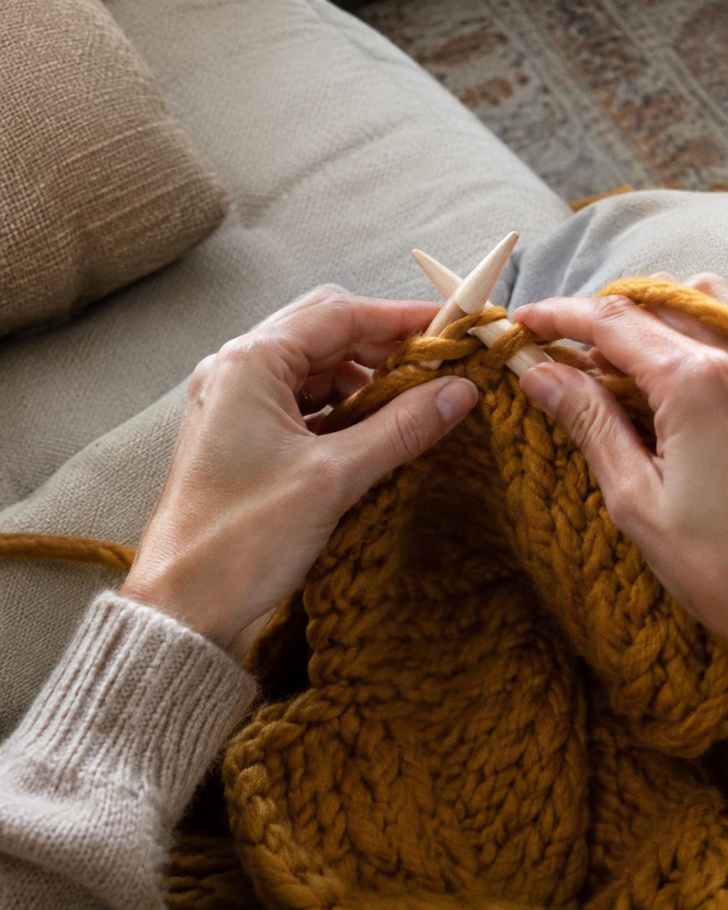 Hands knitting chunky ochre yarn